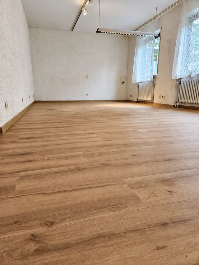 Renovierter Altbauraum mit hellem Holzfußboden und überarbeiteten Wandflächen – aufbereitetes Projektfoto
