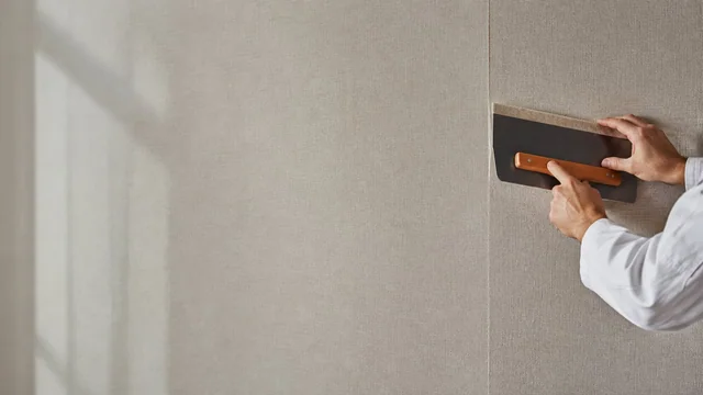 Sorgfältiges Glätten einer Wandbekleidung im Innenraum